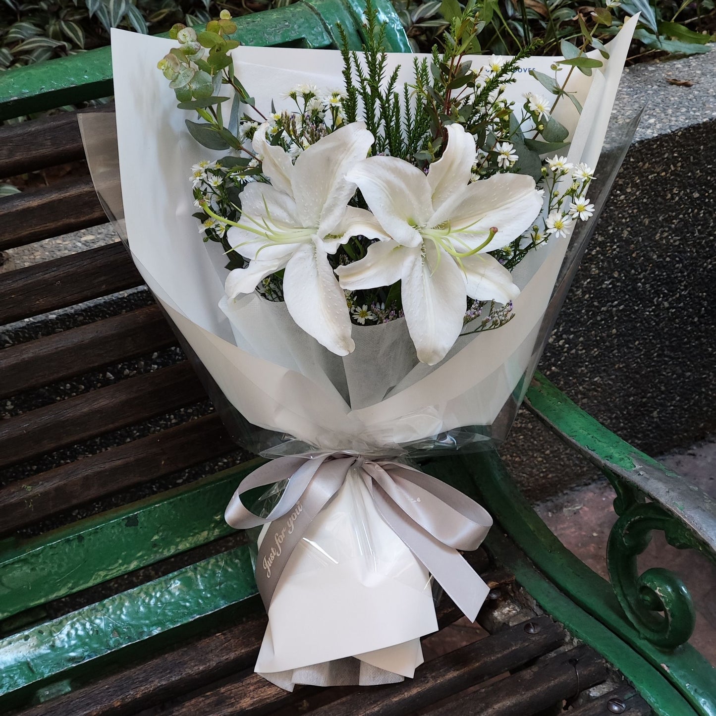 Two White Lilies with Foliage in White Paper Bouquet