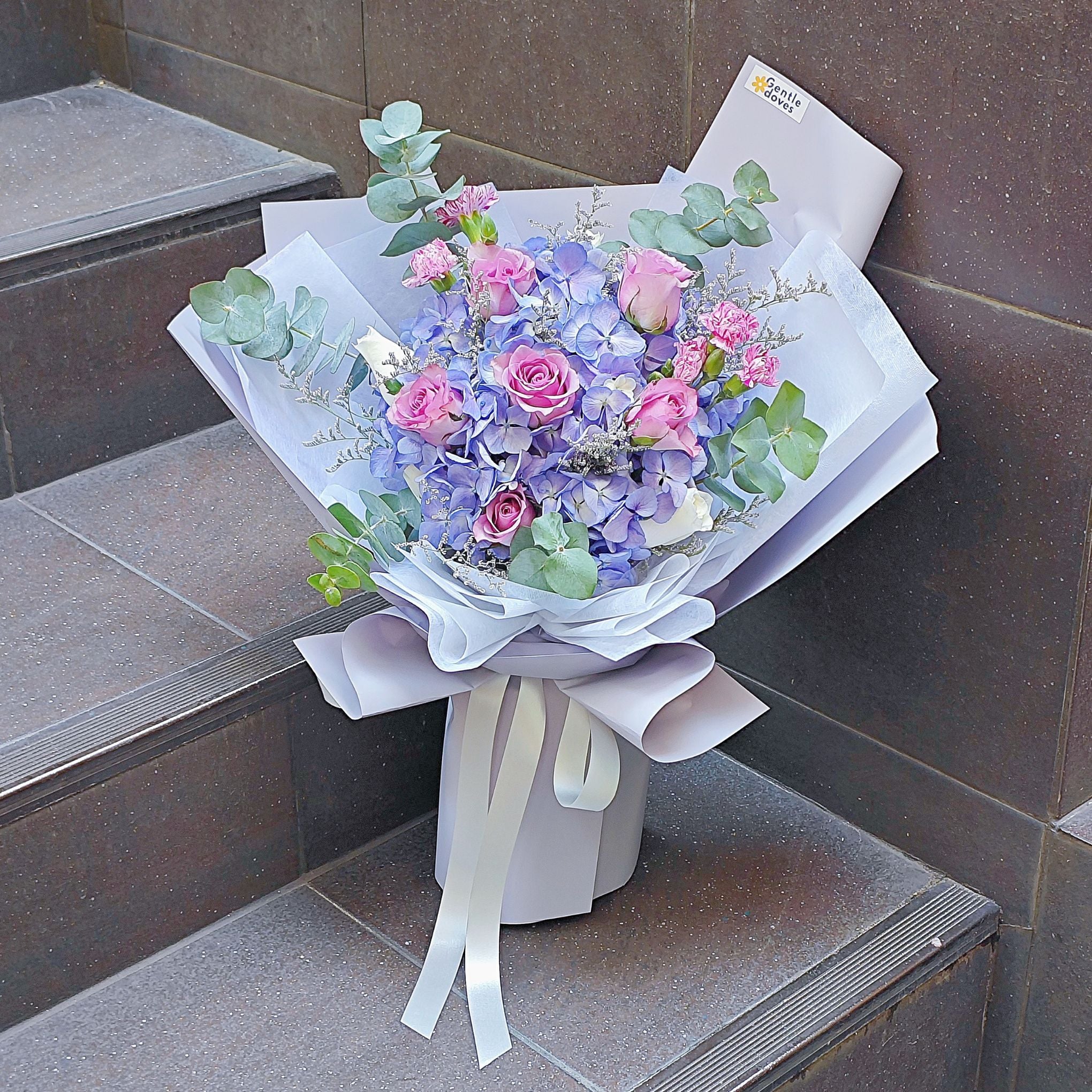 ช่อดอกไฮเดรนเยีย สีม่วง และ กุหลาบโทนสีม่วง กับ ใบไม้แซม ห่อกระดาษสีม่วงพาสเทล