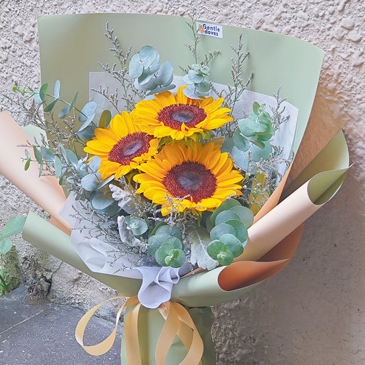 ช่อดอกทานตะวัน 3 ดอก และ ยูคาลิปตัส และ แคสเปียร์ ห่อกระดาษสีเขียว ตัดกระดาษสีส้ม