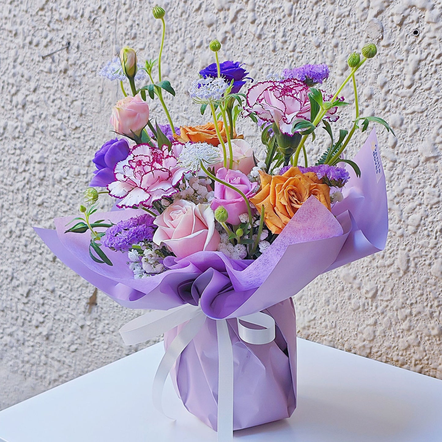 Assorted Purple Color Flowers in Small Vase Arrangement