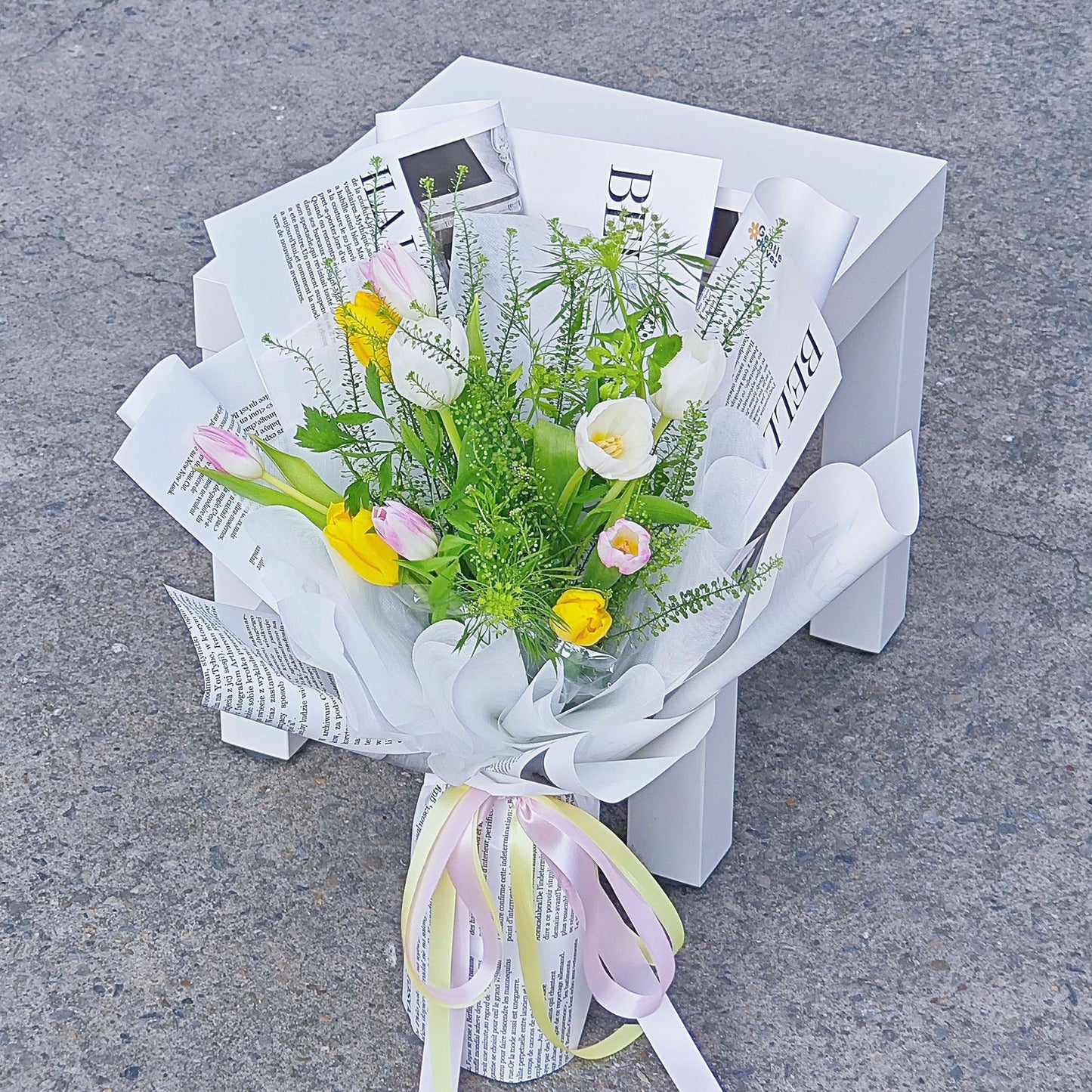 Assorted Ten Tulips in White, Pink and Yellow Colors with Green Foliage in Newspaper Pattern Bouquet