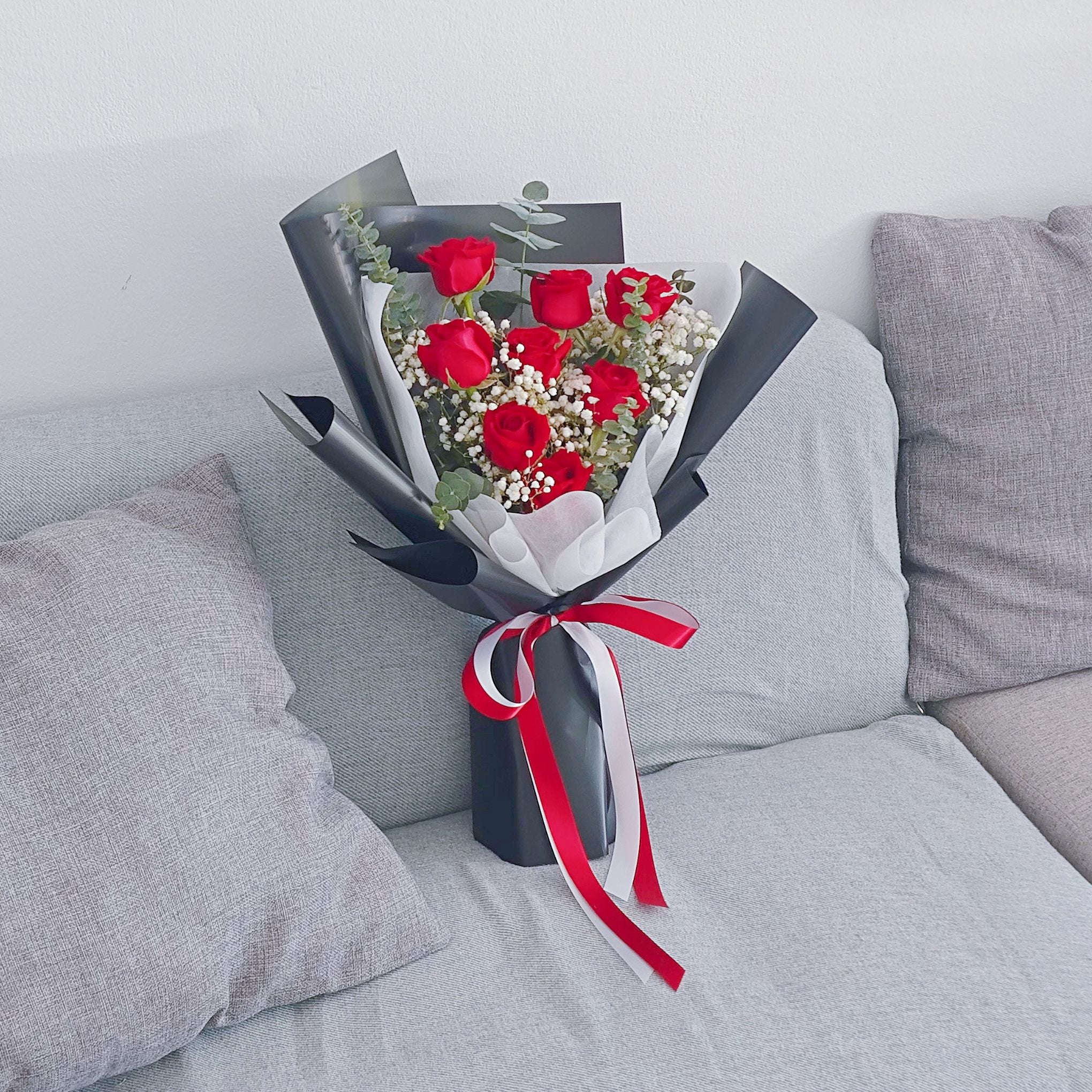 ช่อดอกกุหลาบ สีแดง 8 ดอก และ ใบไม้แซม ห่อกระดาษสีดำ