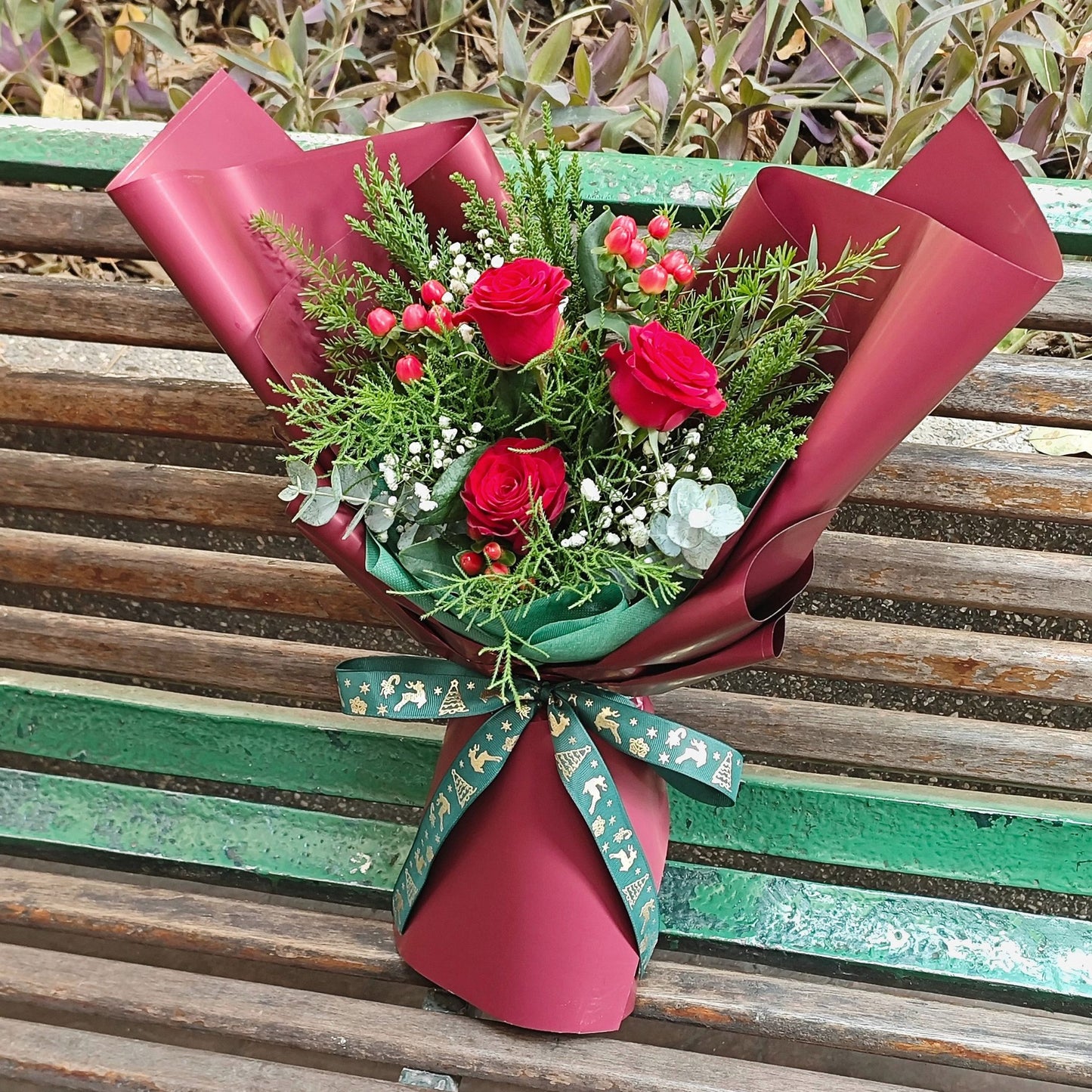 Three Imported Red Roses with Green Pines and Red Berries Bouquet