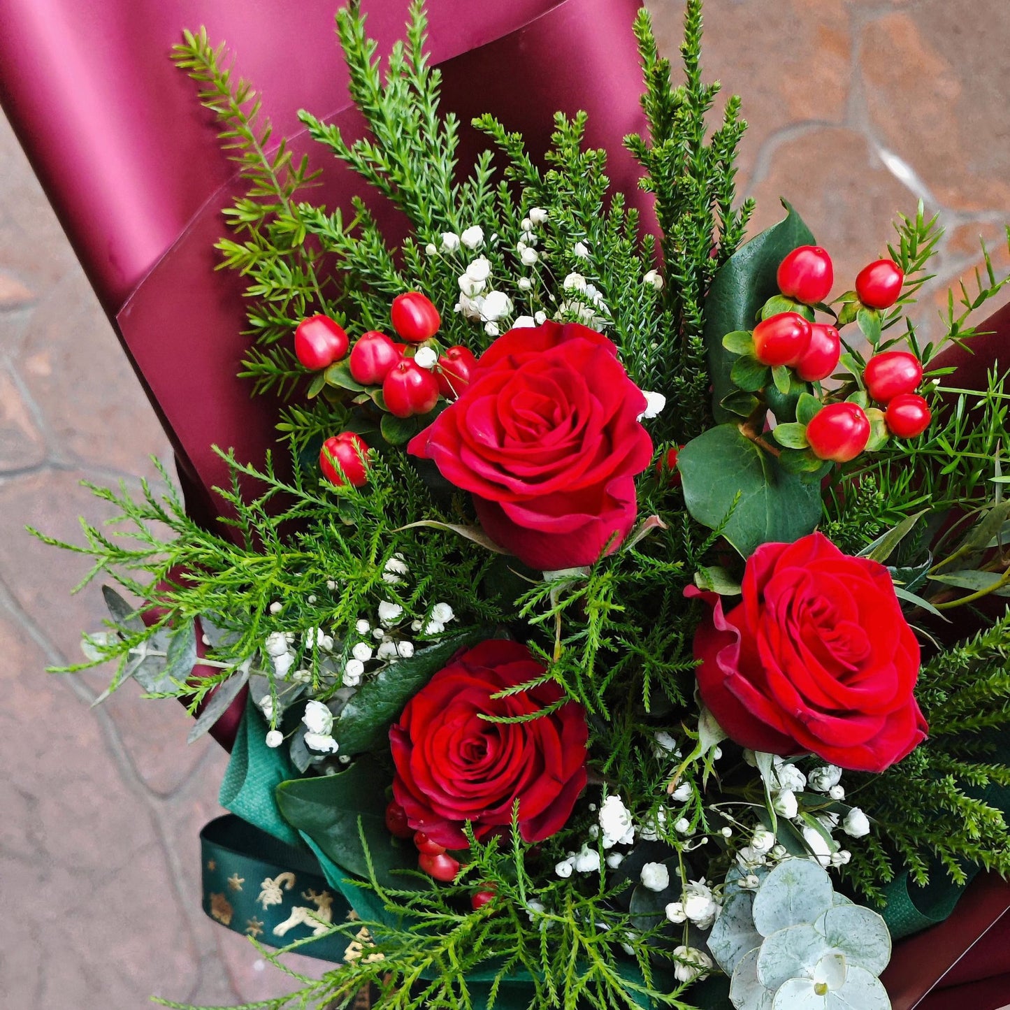 Three Imported Red Roses with Green Pines and Red Berries Bouquet
