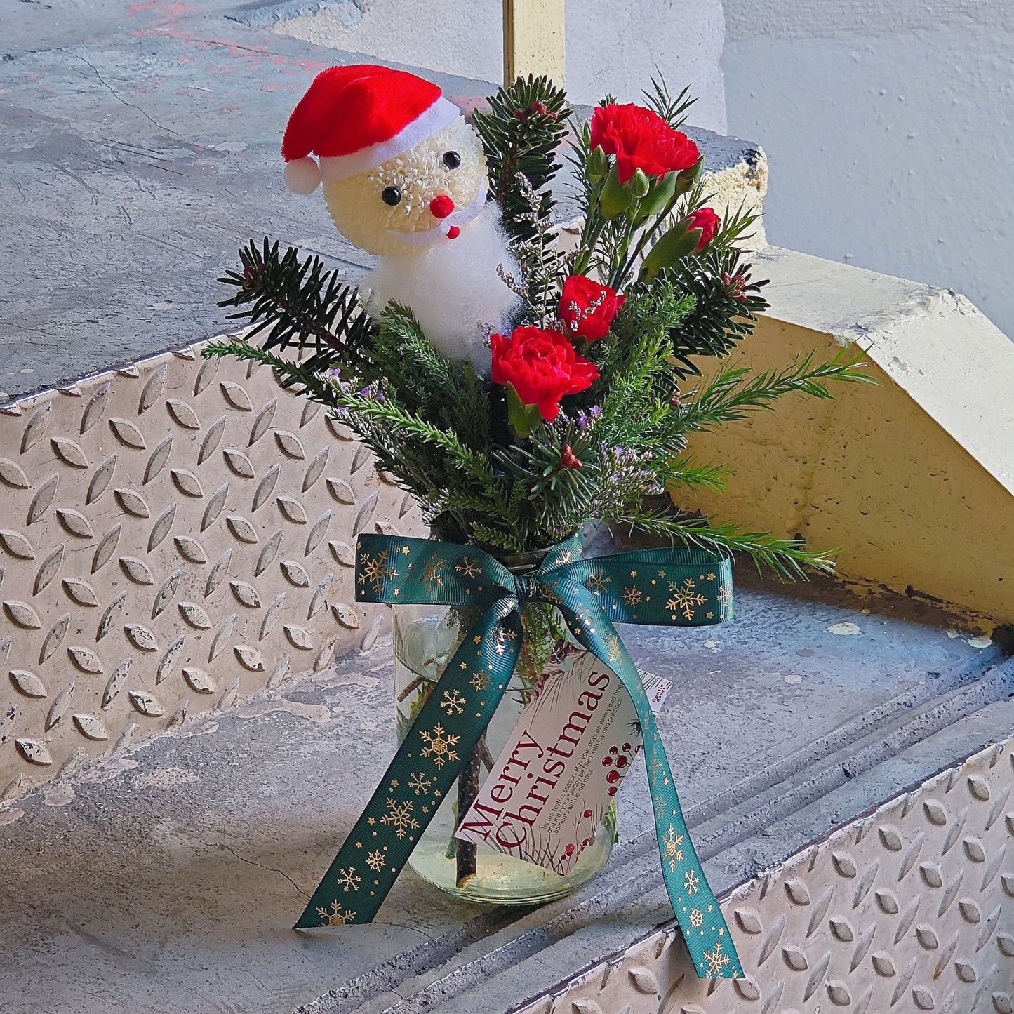 Santa with Green Pines and Red Flowers Small Vase Arrangement