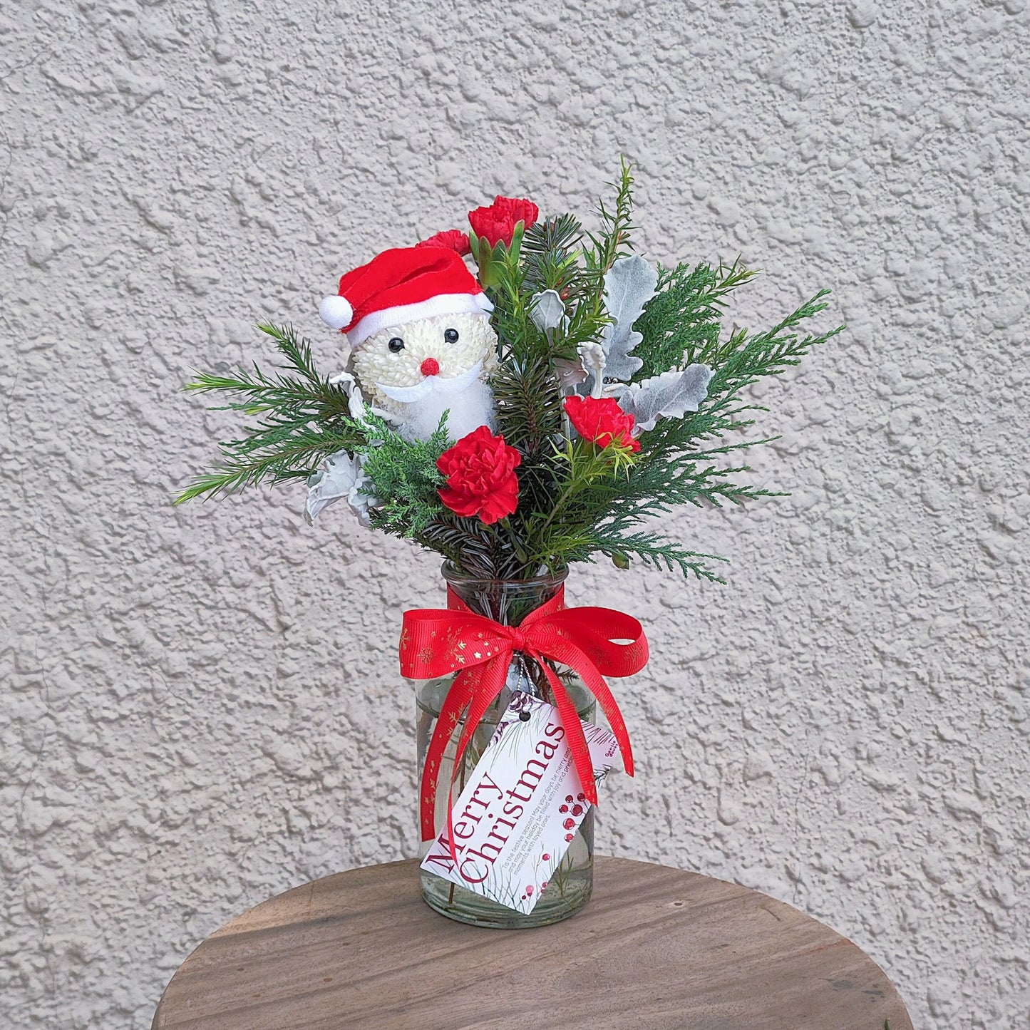 Santa with Green Pines and Red Flowers Small Vase Arrangement
