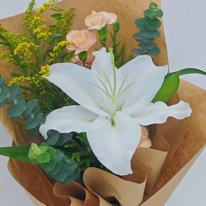 Single White Lily with Sprayed Carnations and Green Foliage in Kraft Paper Small Bouquet