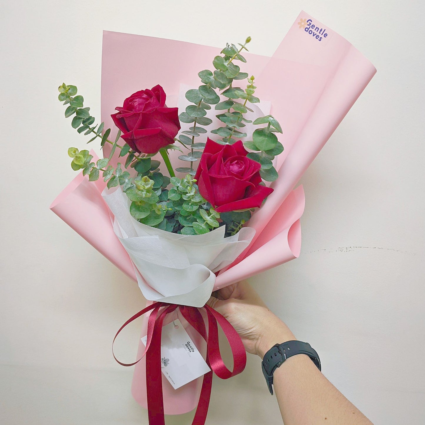 Two Red Roses with Eucalyptus in Pink Paper Bouquet