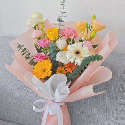 Assorted Yellow and Orange Flowers in Soft Pink Paper Bouquet