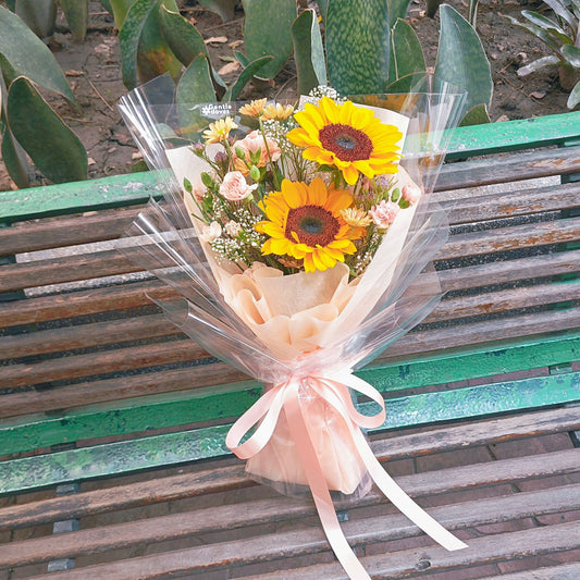 Two Sunflowers with Assorted Orange Flowers in Orange Paper Bouquet