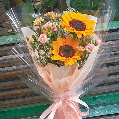 Two Sunflowers with Assorted Orange Flowers in Orange Paper Bouquet