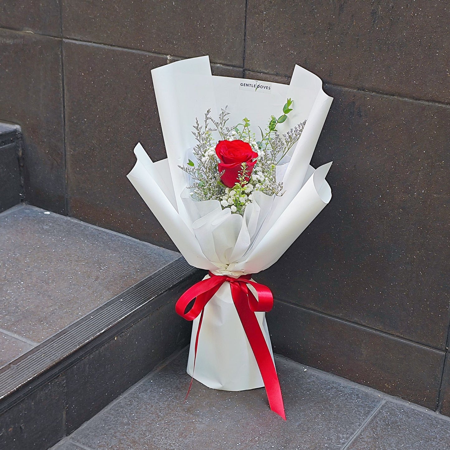 Single Imported Red Rose with Green Foliage in White Paper Bouquet