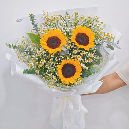 Three Sunflowers with Daisies and Foliage in White Paper Bouquet.