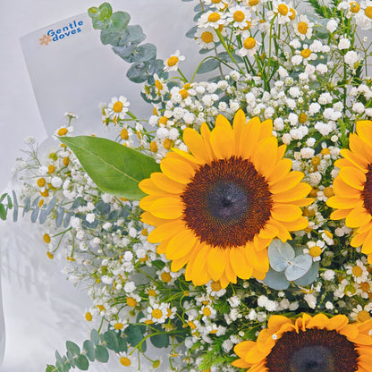 Three Sunflowers with Daisies and Foliage in White Paper Bouquet.