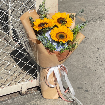 Three Sunflowers with Blue Hydrangeas and Green Foliage in Kraft Paper Bouquet