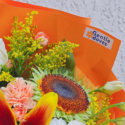 Assorted Orange and Yellow Flowers with Lilies in Vivid Orange Paper Medium Size Bouquet