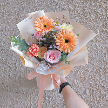 ช่อดอกไม้คละ โทนสีส้มเหลืองอ่อน กับ ดอกไม้โทนสีชมพู ห่อกระดาษสีเหลืองอ่อน ช่อขนาดเล็ก