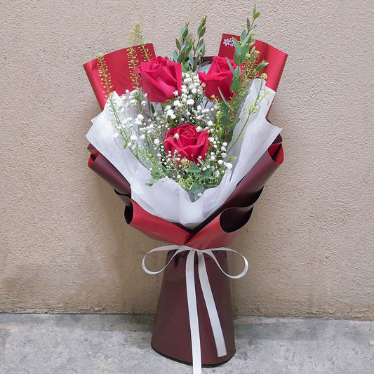 Three Red Roses with Filler Flowers in Red Paper Bouquet