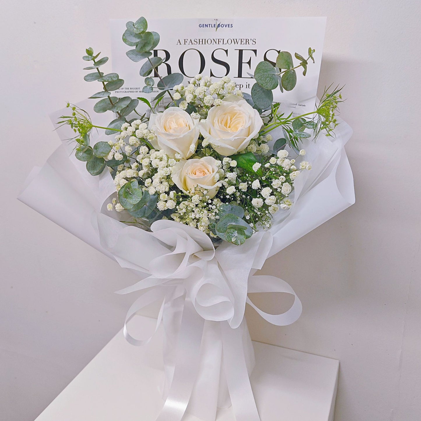 Three White English Roses with Gypsophila and Green Foliage in All White Paper Bouquet