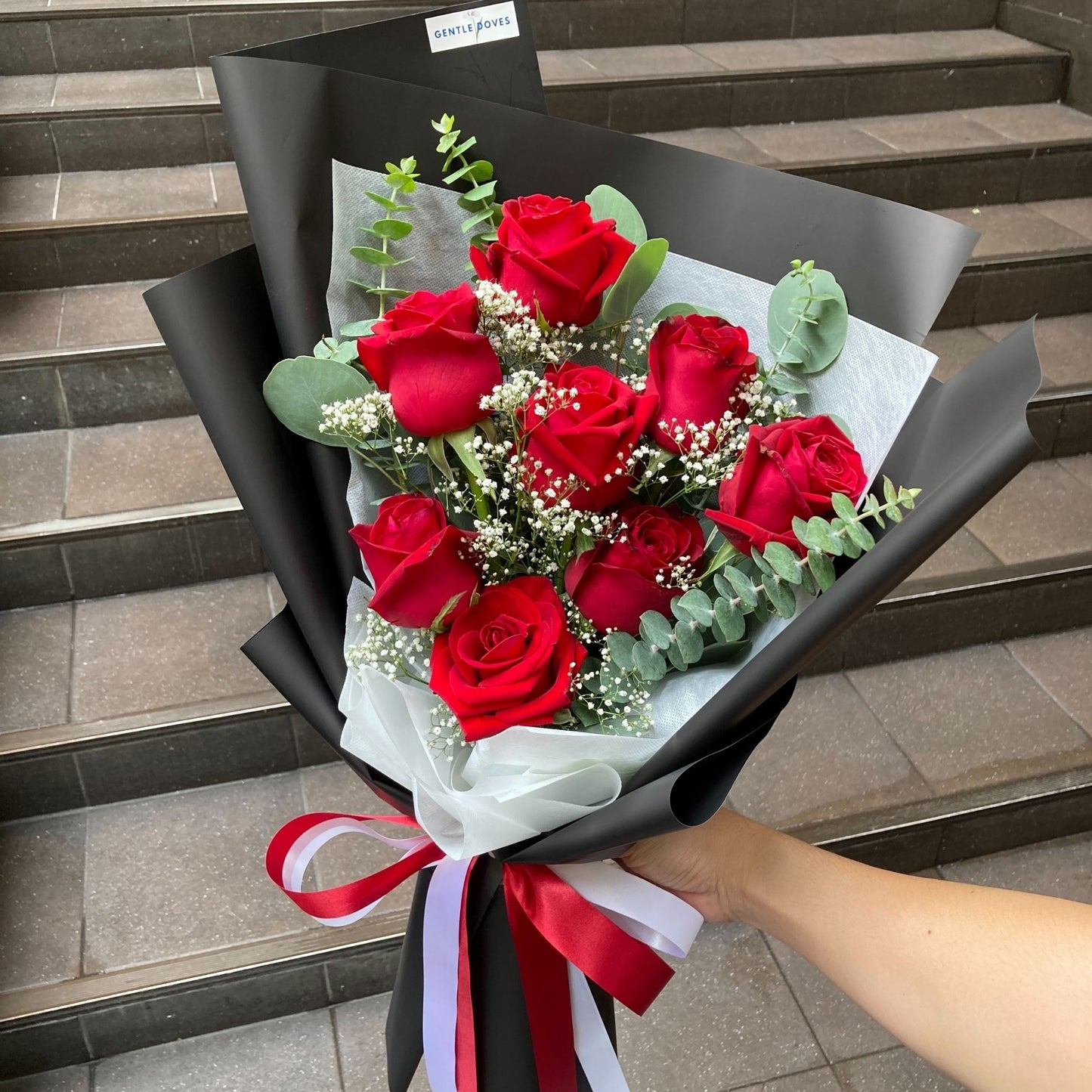 Eight Red Roses with Foliage in Black Paper Bouquet