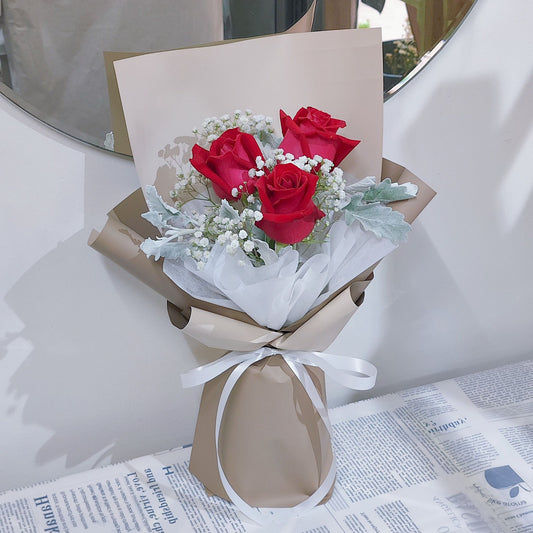 Three Red Roses with Gypsophila and Dusty Miller in Soft Brown Paper Bouquet