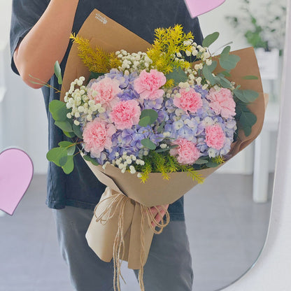 Soft Purple Hydrangeas with Soft Pink Carnations and Green Foliage in Kraft paper Bouquet