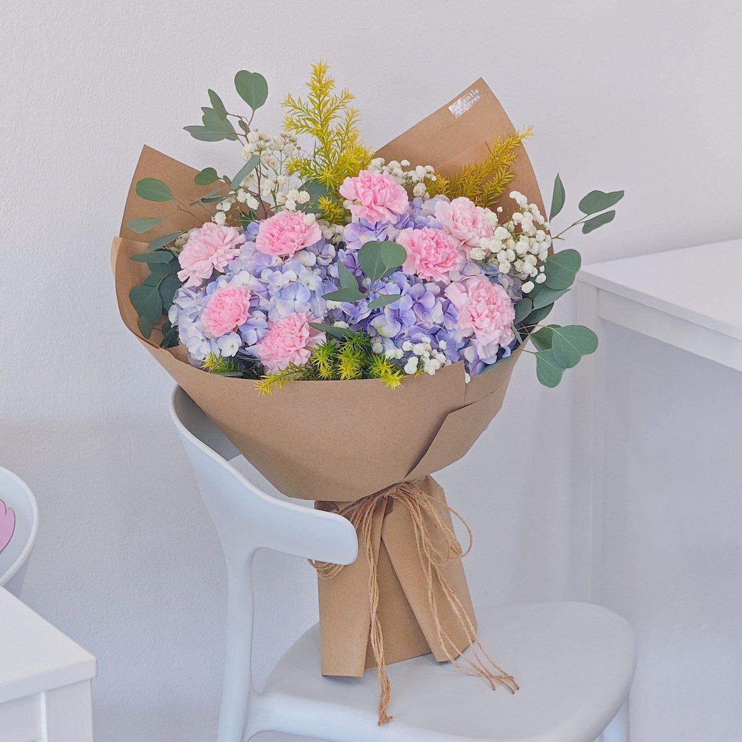 Soft Purple Hydrangeas with Soft Pink Carnations and Green Foliage in Kraft paper Bouquet