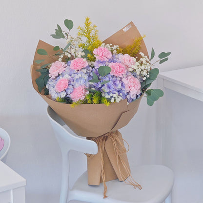 Soft Purple Hydrangeas with Soft Pink Carnations and Green Foliage in Kraft paper Bouquet