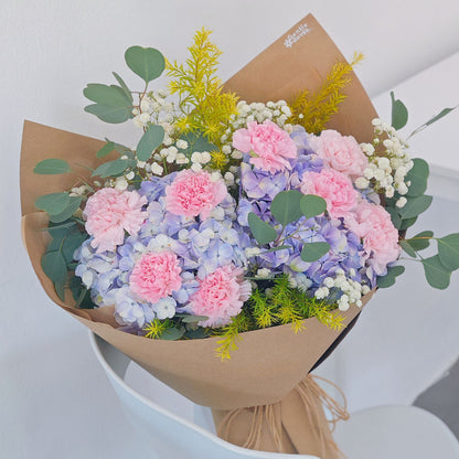 Soft Purple Hydrangeas with Soft Pink Carnations and Green Foliage in Kraft paper Bouquet