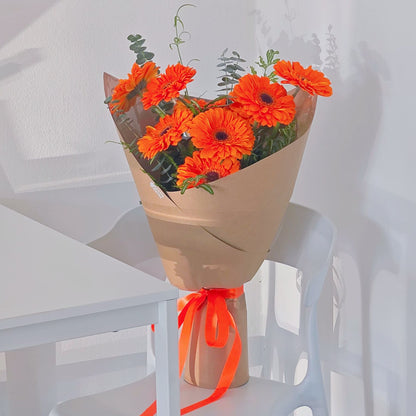 Nine Vivid Orange Gerberas with Green Foliage in Kraft Paper Bouquet