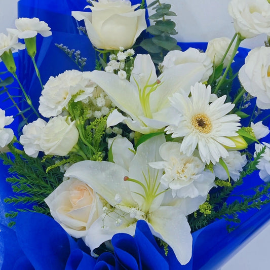 ช่อดอกไม้คละ โทนสีขาว และ ดอกลิลลี่ กับ ใบไม้แซมโทนสีเขียว ห่อกระดาษสีนำเงิน