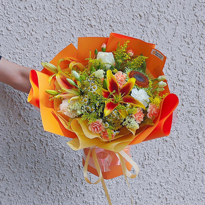 Assorted Orange and Yellow Flowers with Lilies in Vivid Orange Paper Medium Size Bouquet